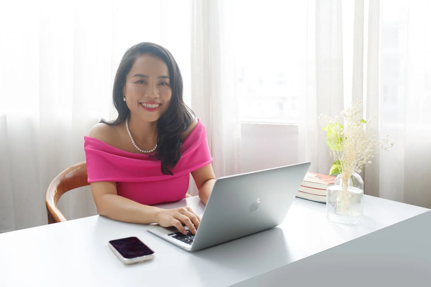 A woman working on a laptop at a home office desk.