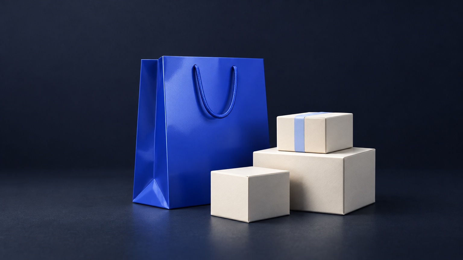 A glossy cobalt shopping bag beside three ivory parcel boxes, one tied with a pale blue band.